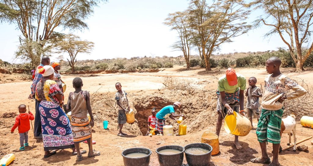 Groupe de personnes creusant de l'eau dans une terre aride.
