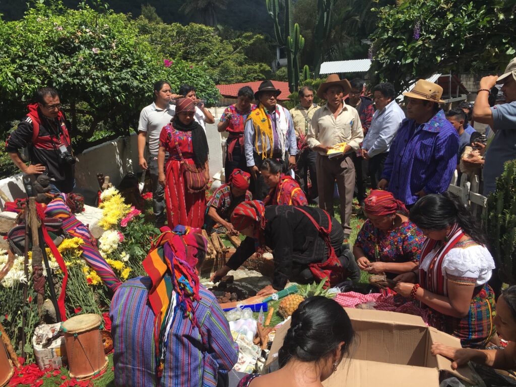 People gather around sellers selling fruits, flowers and drums.